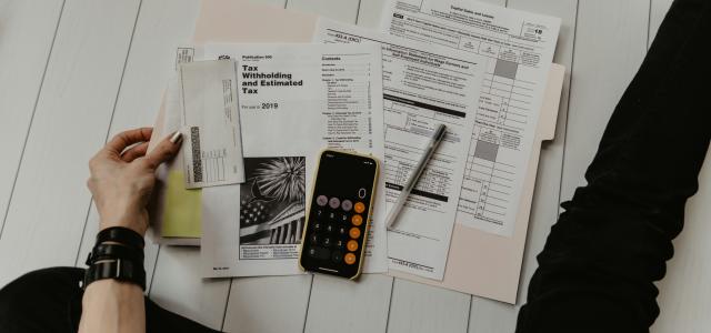 person holding paper near pen and calculator by Kelly Sikkema courtesy of Unsplash.
